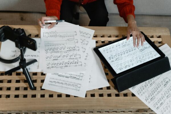 A musician analyzes sheet music on a tablet surrounded by paperwork. Ideal for music production themes.