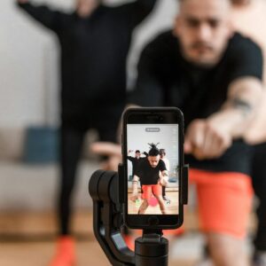 A smartphone records energetic dancers performing indoors, capturing vibrant movement.