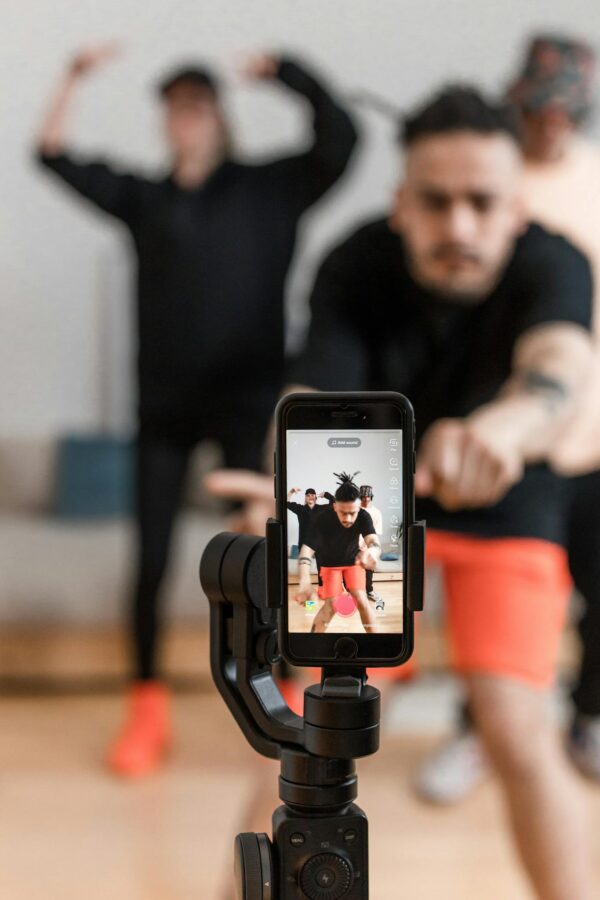 A smartphone records energetic dancers performing indoors, capturing vibrant movement.