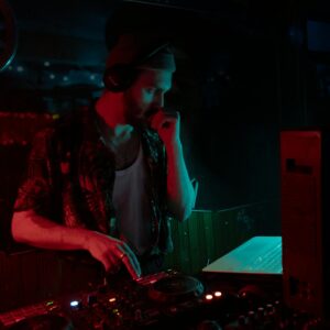 DJ mixing tracks in a dimly lit club with vibrant lighting.