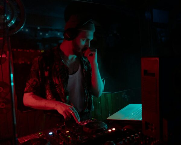 DJ mixing tracks in a dimly lit club with vibrant lighting.