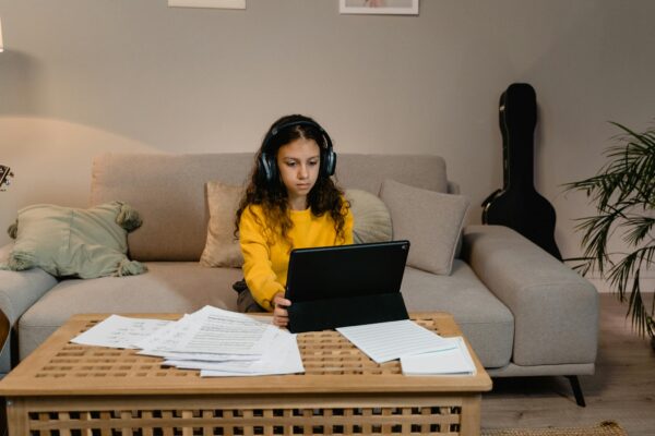 Young girl studying music with a laptop in a cozy living room setting.