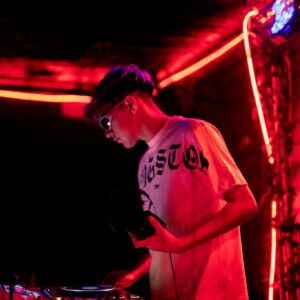 Young Man in Tshirt Mixing Music in Nightclub